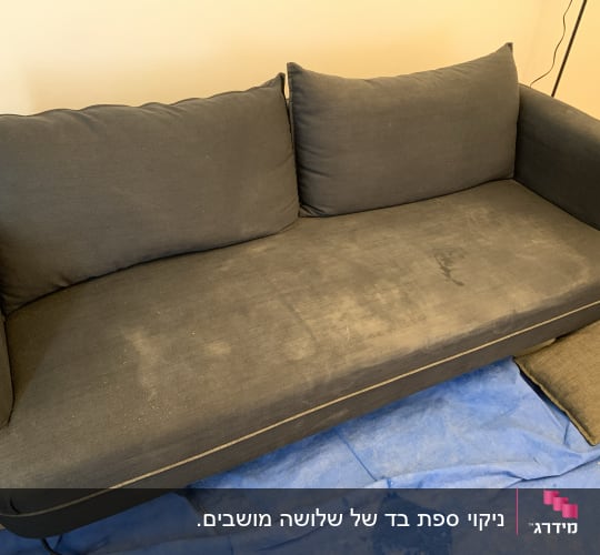 ספה כהה עם כתמים על בד כחול